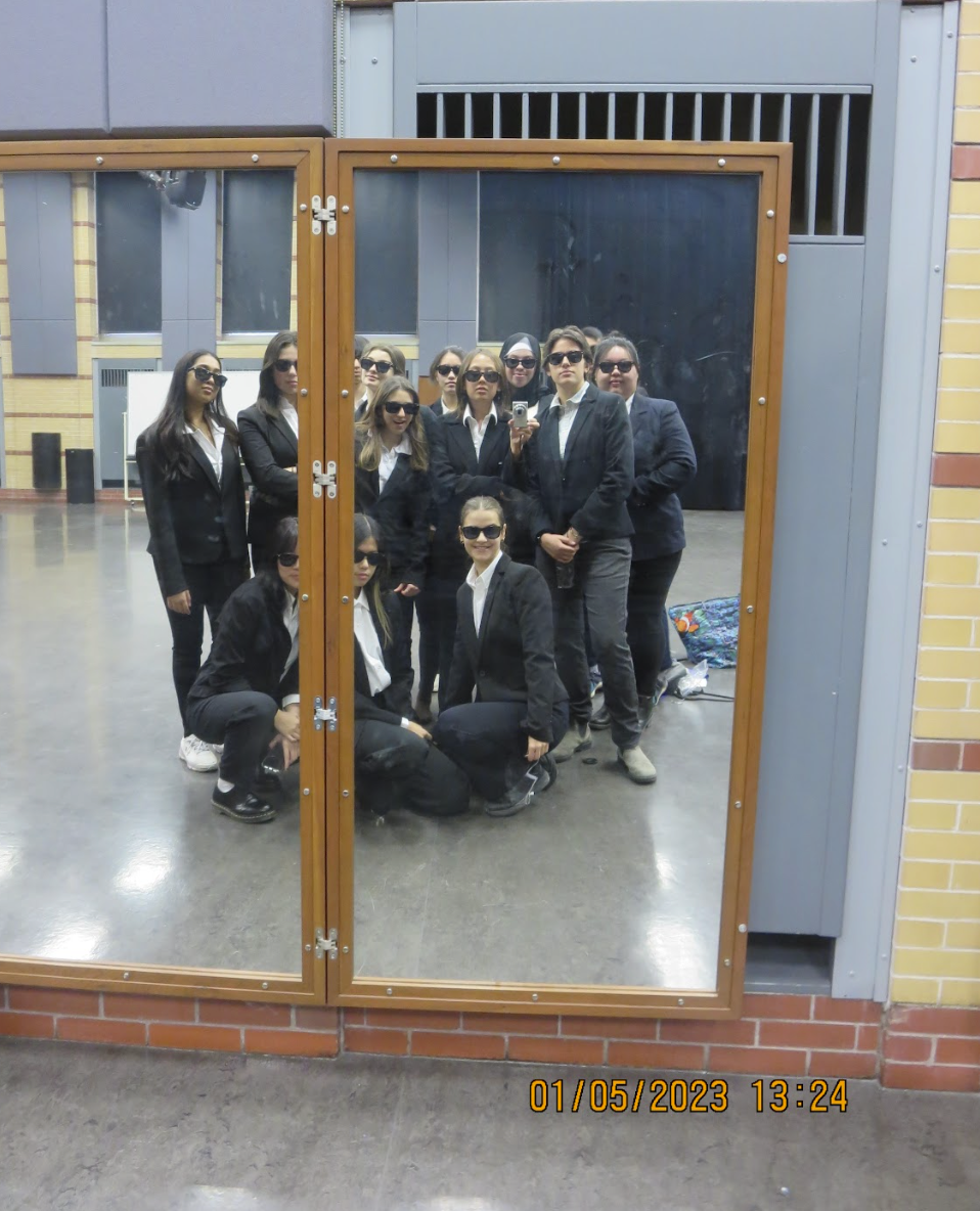 The team posing for a group picture in the mirror in suits